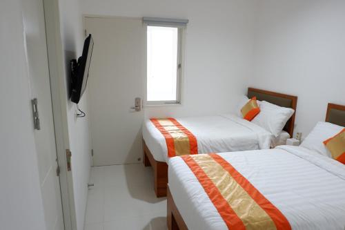 a room with two beds and a television in it at Arawa Traveller's Inn Motel in Makassar