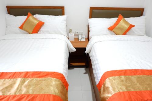 two beds sitting next to each other in a room at Arawa Traveller's Inn Motel in Makassar