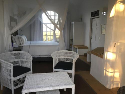 a bedroom with two wicker chairs and a bed at Ashbourne Country Escape Hazyview in Hazyview