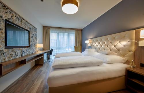 a hotel room with two beds and a flat screen tv at Hotel am See in Regensburg