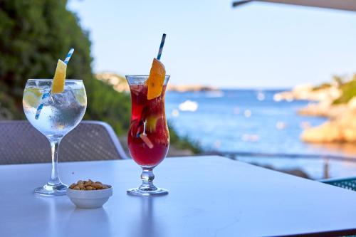 two drinks on a table with a view of the water at Hotel Rocamarina - Adults Only in Cala d´Or