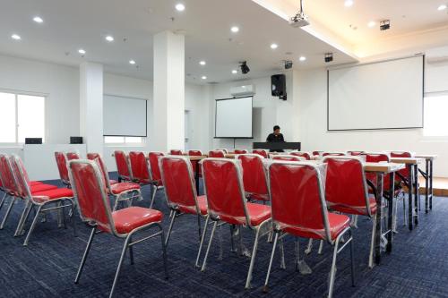 una sala conferenze con sedie rosse e un uomo su un podio di Arawa Traveller's Inn Motel a Makassar