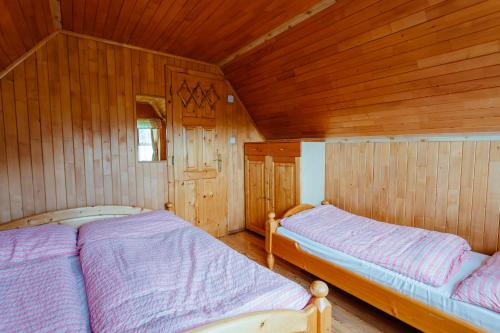two beds in a room with wooden walls at Chata Alpina in Kľačno
