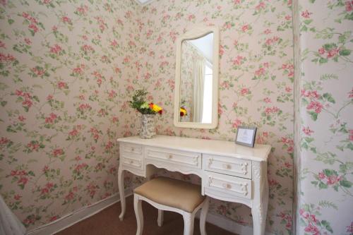 a dressing table and mirror in a room with pink flowers at Blue Bell Hotel in Belford