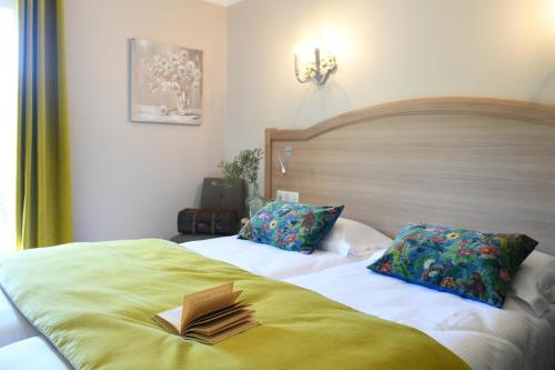 a bedroom with a bed with a book on it at Hôtel Villa Glanum et Spa in Saint-Rémy-de-Provence