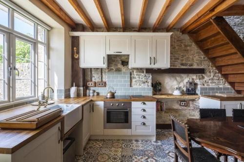 una cucina con armadi bianchi e piano di lavoro di Glatigny Farmhouse - close to beach - proche de la plage a Glatigny