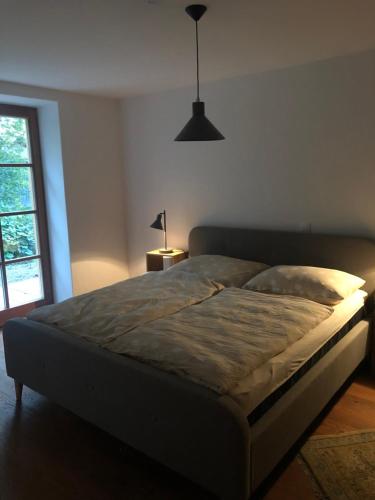 a bed in a bedroom with a lamp and a window at Sonnenhof in Limbach im Burgenland