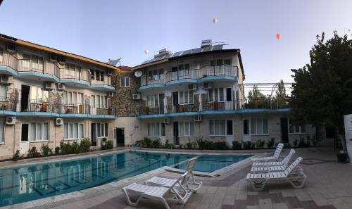 パムッカレにあるDolphin Yunus Hotelのスイミングプール、芝生の椅子2脚が備わるホテルです。