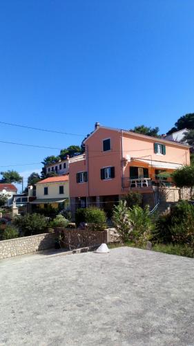 a large building in front of a house at Apartmani Valentina in Veli Lošinj