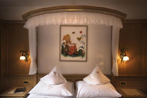 a bedroom with two beds and a picture on the wall at Hotel Garni Concordia - Dolomites Home in Selva di Val Gardena