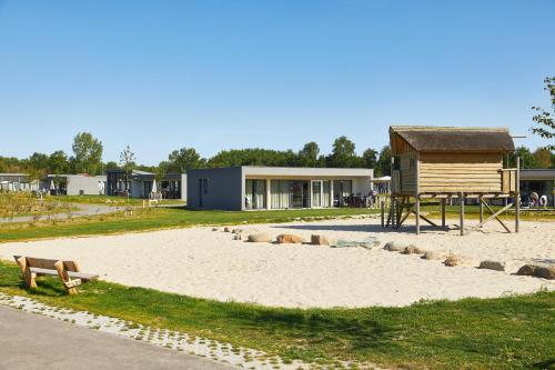 a park with a bench in front of a house at RCN Vakantiepark de Schotsman Bungalow de Bevelander in Kamperland