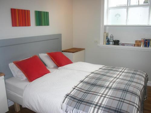 a bed with two red pillows in a bedroom at Nest Apartments in Reykjavík