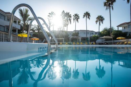 uma piscina num resort com palmeiras em Fuentepark Apartamentos em Corralejo