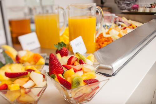 a buffet of fruit in glass bowls and orange juice at Hotel Ariston & Apartments in Varazze
