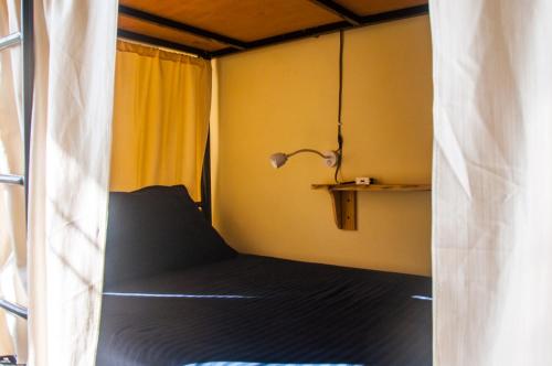 a small bedroom with a bed and a lamp at Hobo Hostel in Dharamshala