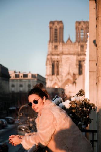 a woman in sunglasses is walking down a city street at La Demeure des Sacres - Cathédrale in Reims