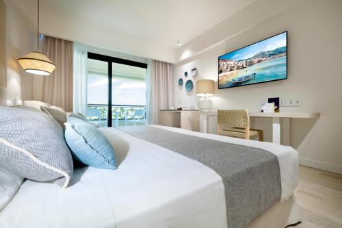 een slaapkamer met een groot wit bed en een bureau bij The Signature Level at Grand Palladium Sicilia Resort & Spa in Campofelice di Roccella