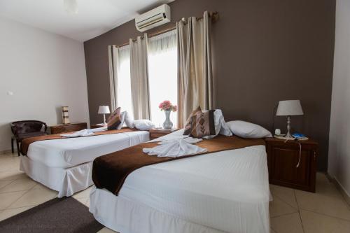 a hotel room with two beds and a window at Bilene Beach House in Vila Praia Do Bilene