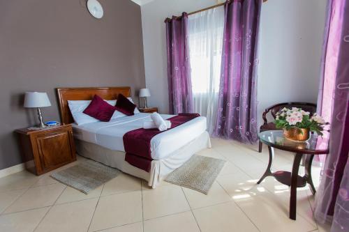 a bedroom with a bed with purple curtains and a table at Bilene Beach House in Vila Praia Do Bilene