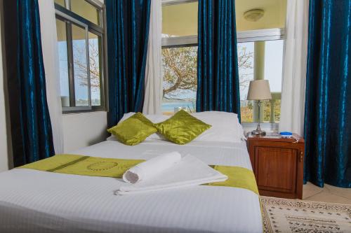 um quarto com uma cama com cortinas azuis e uma janela em Bilene Beach House em Vila Praia do Bilene