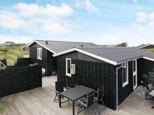 a black shed with a table and chairs on a deck at 7 person holiday home in L kken in Løkken