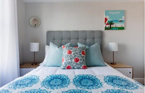 a bedroom with a bed with blue and red pillows at The Paragon Explore Cape Town from a Stylish Home in Cape Town