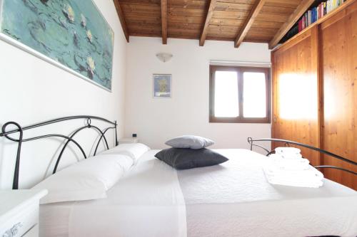 a white bedroom with a bed with white sheets at Appartamento Angela in Selargius