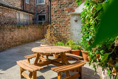 a wooden picnic table and benches in front of a brick building at 3 Claremont Terrace in York
