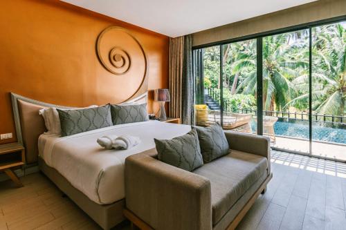 a bedroom with a bed and a couch and a large window at The Tarna Align Resort - SHA Plus in Koh Tao