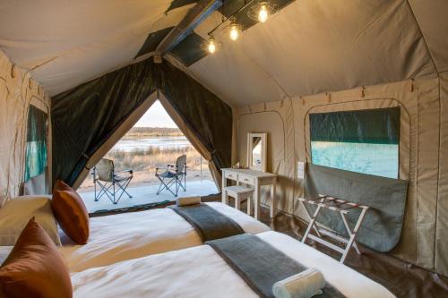 a tent with a bed and a table and chairs at Little Mongena Tented Camp in Klipdrift