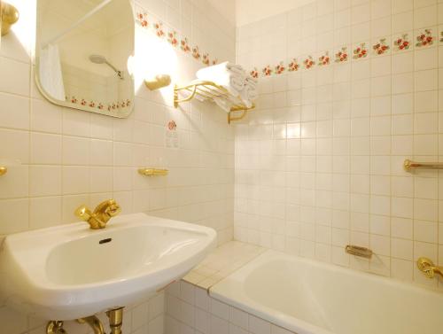 Baño blanco con lavabo y bañera en Ristorante Napoleone en Altheim