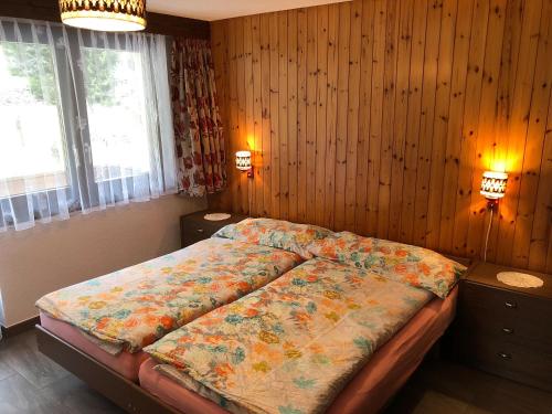 ein Schlafzimmer mit einem Bett in einem Zimmer mit Holzwänden in der Unterkunft Haus Erle in Saas-Grund