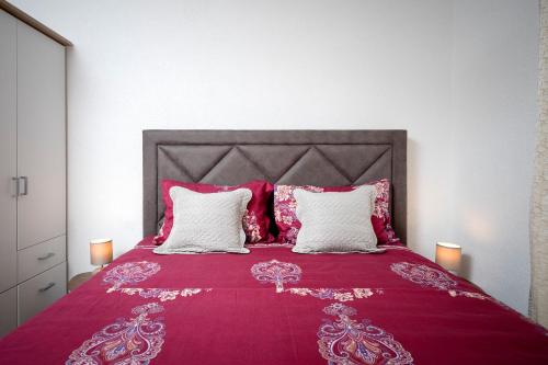 a bedroom with a red bed with white pillows at Villa Vista Hvar in Jelsa