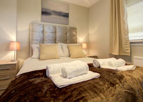 a bedroom with a large bed with towels on it at Struan House in Inverkeithing