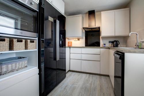 a kitchen with white cabinets and a black refrigerator at Struan House in Inverkeithing