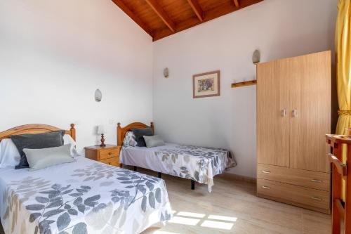 een slaapkamer met 2 bedden en een houten kast bij Flatguest Chozo del viejo - Peaceful country Villa in La Antigua in Valle de Santa Inés