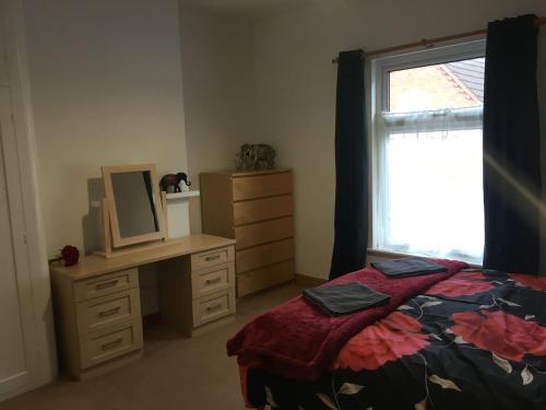 a bedroom with a bed and a dresser and a window at 5 Bedroom House For Corporate Stays in Kettering in Kettering