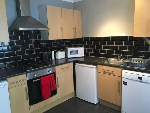 a kitchen with white appliances and black tiles on the wall at 5 Bedroom House For Corporate Stays in Kettering in Kettering