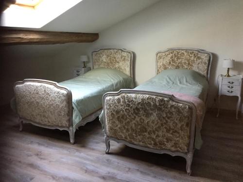 two beds in a room with two chairs at Chez Mémère Hélène in Sormonne