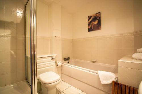a bathroom with a toilet and a tub and a sink at Turnberry Apartments in Turnberry