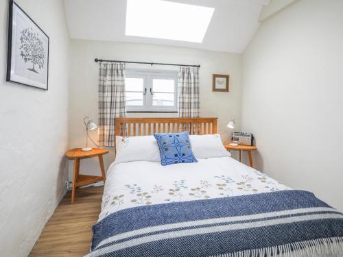 ein Schlafzimmer mit einem Bett mit einer blauen und weißen Decke in der Unterkunft Ffrwd Cottage in Bodorgan