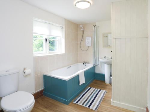 ein Badezimmer mit einer Badewanne, einem WC und einem Waschbecken in der Unterkunft Ffrwd Cottage in Bodorgan