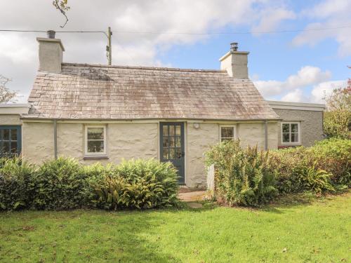 an old white house with a roof at Ffrwd Cottage in Bodorgan