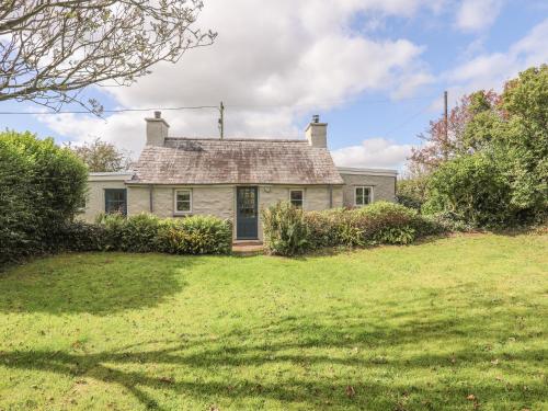 an old white house with a grass yard at Ffrwd Cottage in Bodorgan