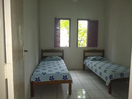 two beds in a room with two windows at Residencial Ravasco in Camamu