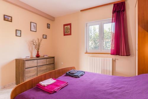 a bedroom with a purple bed and a window at Appartamenti Valentina-no groups in Banjole