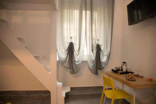 Zimmer mit einem Fenster mit einem Tisch und gelben Stühlen in der Unterkunft PALAZZIELLO MATERDEI in Neapel