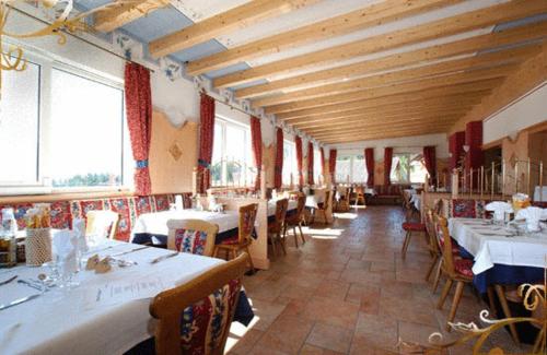 a dining room with tables and chairs and windows at Family & Wellness Hotel Fontana in Vigo di Fassa