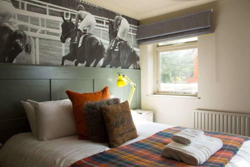 um quarto com uma cama com uma fotografia de cavalo na parede em The Evenlode Hotel em Witney