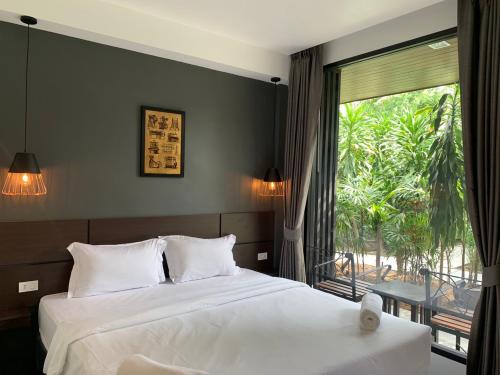 a bedroom with two beds and a large window at The CHESS Samui in Chaweng
